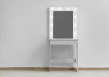 Duvarında büyük bir ayna ve ışıklar olan beyaz makyaj masası. Makyaj sanatçısının iş yeri, modern soyunma odası..