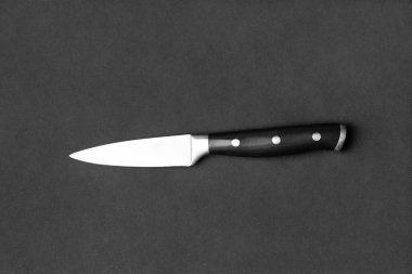 Kitchen knife with a black handle on a black background. Knife on a dark background top view. Kitchenware. Knife with a wide blade.