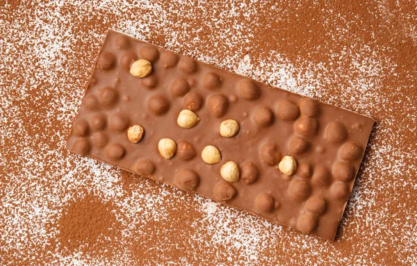 Milk Chocolate Hazelnuts Lies White Background Sprinkled Cocoa Powder Top — Zdjęcie stockowe
