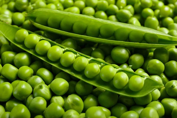 新鮮な緑のエンドウ豆の背景 開いているポッドは 皮をむいた甘いエンドウ豆の粒 トップビュー クローズアップにあります 野菜の背景 野菜のタンパク質 健康的な製品 — ストック写真