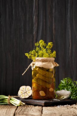 Kavanozda salatalık turşusu, taze salatalık, ahşap arka planda sarımsak. Korunmak için biber, soğan ve taze salatalık. Salatalık salatası..