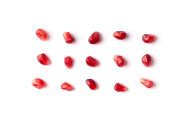 Red grains of a ripe pomegranate are neatly laid out on a white background top view. Pomegranate grains on isolated. Background of pomegranate seeds.
