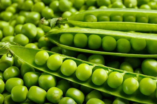 新鮮な緑のエンドウ豆の背景 開いているポッドは 皮をむいた甘いエンドウ豆の粒 トップビュー クローズアップにあります 野菜の背景 野菜のタンパク質 健康的な製品 — ストック写真