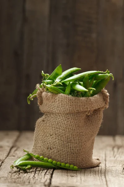 ラップバッグに新鮮な緑のエンドウ豆のポッド 閉じた甘い有機緑のエンドウ豆 高齢者の木製の背景に開いたポッド 植物性タンパク質健康的な製品 — ストック写真
