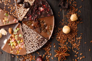 Şekerleme, fındık, kuru böğürtlen, çikolatalı pizza ve koyu ahşap arka planda malzemelerle pizza şeklinde yaratıcı kompozisyon çikolatası..