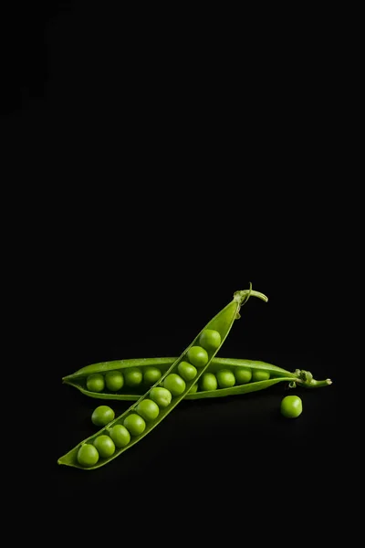 黒の背景に大きな粒を持つ新鮮な緑のエンドウ豆の閉じた開いたポッド クローズアップ 野菜タンパク質 ベジタリアン向け製品 — ストック写真