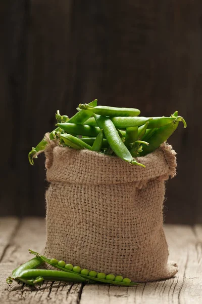 ラップバッグに新鮮な緑のエンドウ豆のポッド 閉じた甘い有機緑のエンドウ豆 高齢者の木製の背景に開いたポッド 植物性タンパク質健康的な製品 — ストック写真