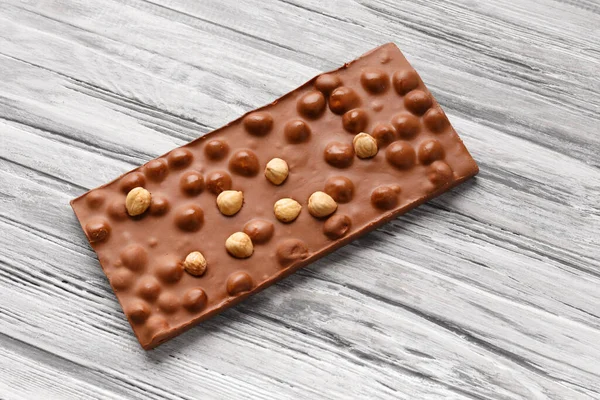 Handmade chocolate with whole hazelnuts on a gray wooden background, top view, space for text, milk chocolate bar with nuts, concept for patisserie.