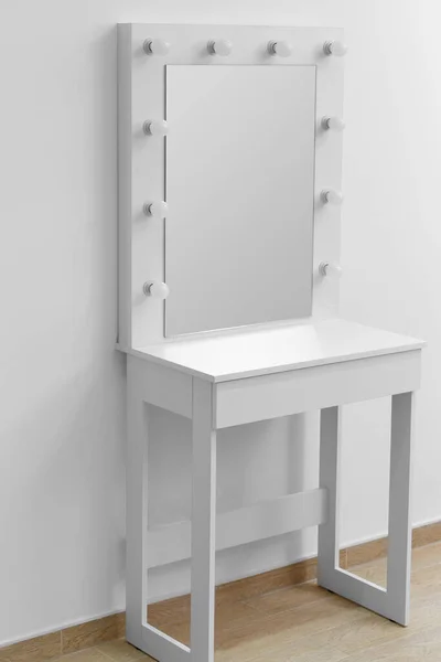 White makeup dressing table with a large mirror and lamps against a white wall. Makeup artist\'s workplace, modern dressing room.