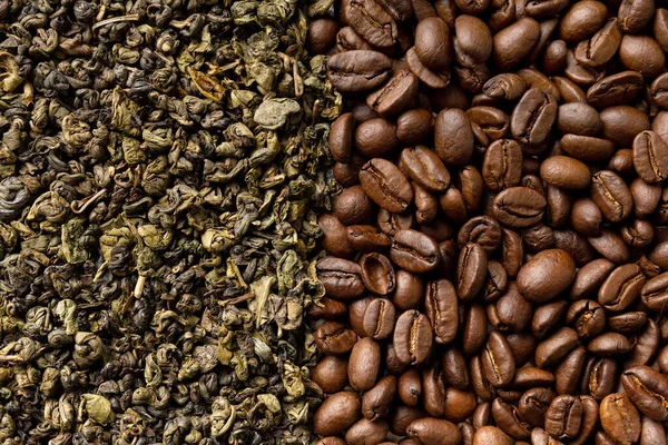 Background of dry green tea leaves and roasted coffee beans close-up with space for text.