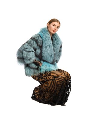 Lüks kürklü ve beyaz arka planda poz veren uzun elbiseli güzel bir kız model. Kıyafet reklamı, kürkten yapılmış şık dış giyim.