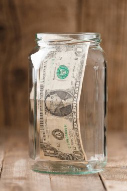 Ahşap bir arka planda cam bir kavanozda bir dolar banknot, tasarruf konsepti, para rezervi, mali yatırım, nakit birikimi.
