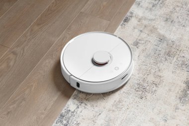 Halıdaki ve laminattaki robot süpürge tozu kaldırıyor. Akıllı ev kavramı, kablosuz temizlik, herhangi bir yüzeyde akıllı bir elektrik süpürgesi..