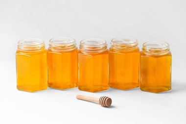 Kavanozların kavramsal bileşimi bal peteği ve izolasyon üzerine ahşap kaplama. Beyaz arka planda aynı şekil ve boyutta cam kavanozları aç..