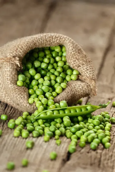 新鲜的有机豌豆皮在麻袋中 开放的绿色豌豆豆荚 分散成熟豌豆种子在老化的木制背景 植物蛋白 健康产品 — 图库照片