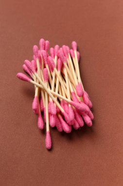 Bambu pamuk çubukları kahverengi arka plana yapışır, üst manzara. Hijyen, makyaj ve ilaç için çevre dostu eşyalar.