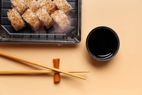 Sushi rolls with salmon in a plastic package, Chinese sticks, soy sauce on a light background, top view. Delivery of sushi, rolls in a takeaway package.