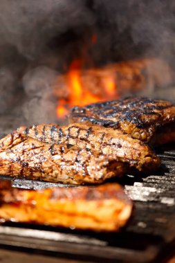 İştah açıcı baltalı biftekler, pirzola ve sığır filetosu ızgara yaparken ızgarada kızartılıyor. Restoranda ızgara et..