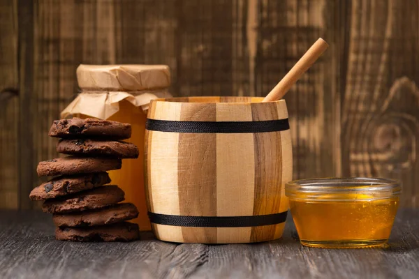 木の背景にチョコレートチップが付いた瓶やボウル ディッパー 自家製クッキーで蜂蜜 クラフトチョコレートクッキーと蜂蜜の構成 — ストック写真