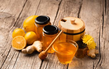 Kavanozda bal, bir kase ve ahşap fıçı, limon, ahşap arka planda zencefil. Bağışıklığı geliştiren organik ürünler, soğuk algınlığı tedavisi.