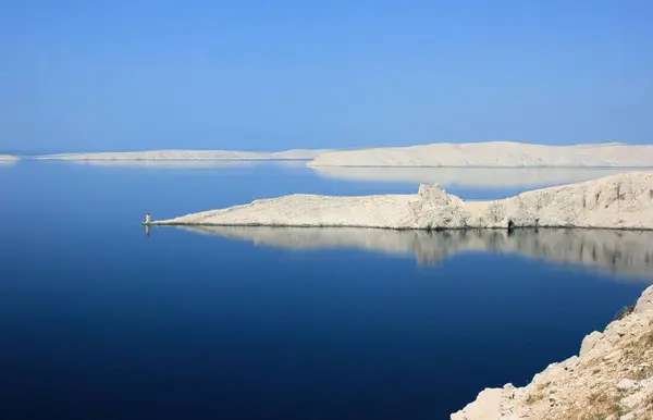 stock image reflections of the Fortica fort in the blue sea, near he bridge to the island Pag, Croatia