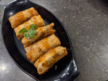 Kızarmış karamelli muz, siyah tabak ve gri arka plan. Fotoğraf yemek arkaplanı, poster ve yemek içeriği için kullanılabilir.