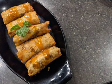 Kızarmış karamelli muz, siyah tabak ve gri arka plan. Fotoğraf yemek arkaplanı, poster ve yemek içeriği için kullanılabilir.