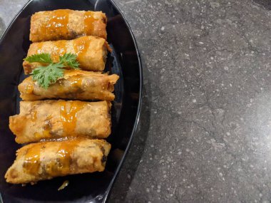 Kızarmış karamelli muz, siyah tabak ve gri arka plan. Fotoğraf yemek arkaplanı, poster ve yemek içeriği için kullanılabilir.