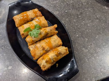 Kızarmış karamelli muz, siyah tabak ve gri arka plan. Fotoğraf yemek arkaplanı, poster ve yemek içeriği için kullanılabilir.