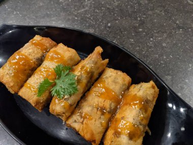 Kızarmış karamelli muz, siyah tabak ve gri arka plan. Fotoğraf yemek arkaplanı, poster ve yemek içeriği için kullanılabilir.