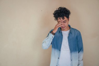 Genç kıvırcık adam depresyon yüzlü kot pantolon giyiyor. Bu fotoğraf, erkek ifadesi reklamcılığı ve moda yaşam tarzı için uygun..