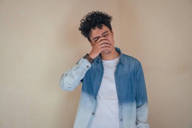 Genç kıvırcık adam depresyon yüzlü kot pantolon giyiyor. Bu fotoğraf, erkek ifadesi reklamcılığı ve moda yaşam tarzı için uygun..