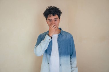 Genç kıvırcık adam kot pantolon giyip teşekkür ediyor. Bu fotoğraf, erkek ifadesi reklamcılığı ve moda yaşam tarzı için uygun..