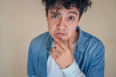 Genç kıvırcık adam kot pantolon giyip teşekkür ediyor. Bu fotoğraf, erkek ifadesi reklamcılığı ve moda yaşam tarzı için uygun..