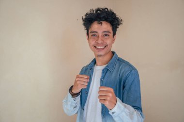 Genç kıvırcık adam dövüş pozuyla kot elbise giyiyor. Bu fotoğraf, erkek ifadesi reklamcılığı ve moda yaşam tarzı için uygun..