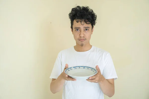 Молодой Индонезиец Держит Пустую Тарелку Грустным Выражением Лица Фотография Подходит — стоковое фото
