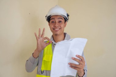 Genç inşaatçı kontrol raporu ver sonra poz ver ve hareket et. Fotoğraf küçük resim tıklama ve reklam ekommersi için kullanılabilir.