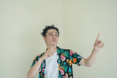 Kıvırcık adam Endonezyalı plaj kıyafeti dansını giyer ve müzik jestinin tadını çıkarır. Bu fotoğraf, erkek ifadesi reklamcılığı ve moda yaşam tarzı için uygun..