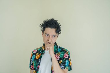 Kıvırcık adam düşünme duruşu ve jesti olan plaj giysileri giyer. Fotoğraf, insan ifadesi reklamcılığı ve ekommerce içeriği medyası için kullanılabilir.