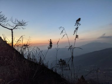 Güneşin doğuşuyla dağ manzarası mavi ve güzel bir manzara. Fotoğraf macera içeriği medyası, doğa posteri ve orman geçmişi için kullanılabilir.