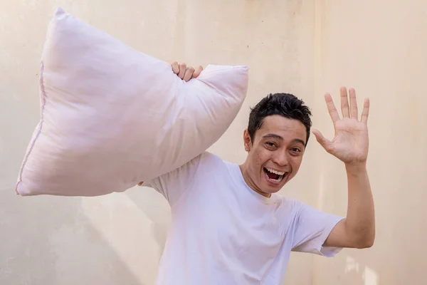 インドネシア人の男は 枕が友人と戦うとき 幸せな表情でポーズとジェスチャーをします 写真は 男性の表現広告やファッションライフスタイルに使用するのに適しています — ストック写真