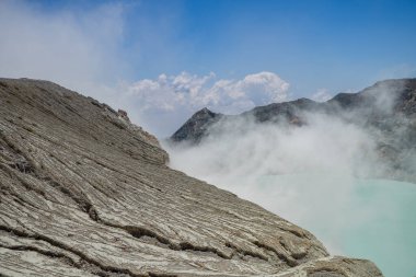 İjen Dağı volkanik krateri gündüz vakti mavi ateş ve göl. Fotoğraf macera içeriği medyası, doğa posteri ve orman geçmişi için kullanılabilir.