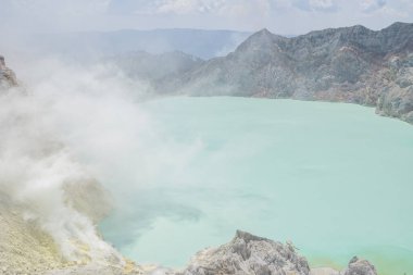 İjen Dağı volkanik krateri gündüz vakti mavi ateş ve göl. Fotoğraf macera içeriği medyası, doğa posteri ve orman geçmişi için kullanılabilir.