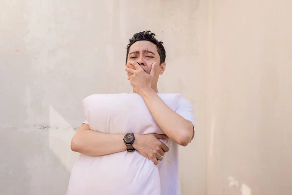 印尼男人感到懒惰和困倦 抱着枕头 穿着白色的T恤 这张照片适用于男性表达广告和时尚生活方式 — 图库照片