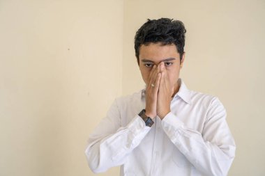 Endonezyalı ofis çalışanı beyaz kıyafetler giyiyor. Stres ve mutsuz bir ifade var. Bu fotoğraf, erkek ifadesi reklamcılığı ve moda yaşam tarzı için uygun..