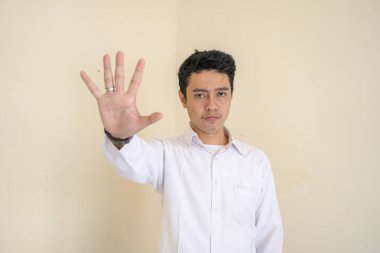 Genç Endonezyalı kıvırcık adam dur pozuyla beyaz elbiseler giyiyor. Bu fotoğraf, erkek ifadesi reklamcılığı ve moda yaşam tarzı için uygun..