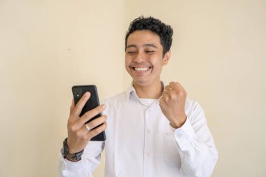 Endonezyalı ofis çalışanı iş saatinde beyaz kıyafetler giyer ve oyun oynarken mutlu olur. Bu fotoğraf, erkek ifadesi reklamcılığı ve moda yaşam tarzı için uygun..