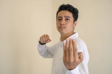 Genç Endonezyalı kıvırcık adam dövüş pozu veren beyaz elbiseler giyiyor. Bu fotoğraf, erkek ifadesi reklamcılığı ve moda yaşam tarzı için uygun..