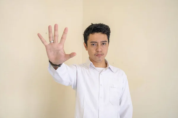 Young Indonesian curly man wear white clothes with stop pose. The photo is suitable to use for man expression advertising and fashion life style.