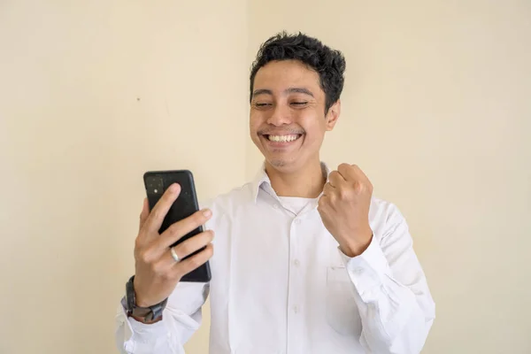 Endonezyalı ofis çalışanı iş saatinde beyaz kıyafetler giyer ve oyun oynarken mutlu olur. Bu fotoğraf, erkek ifadesi reklamcılığı ve moda yaşam tarzı için uygun..